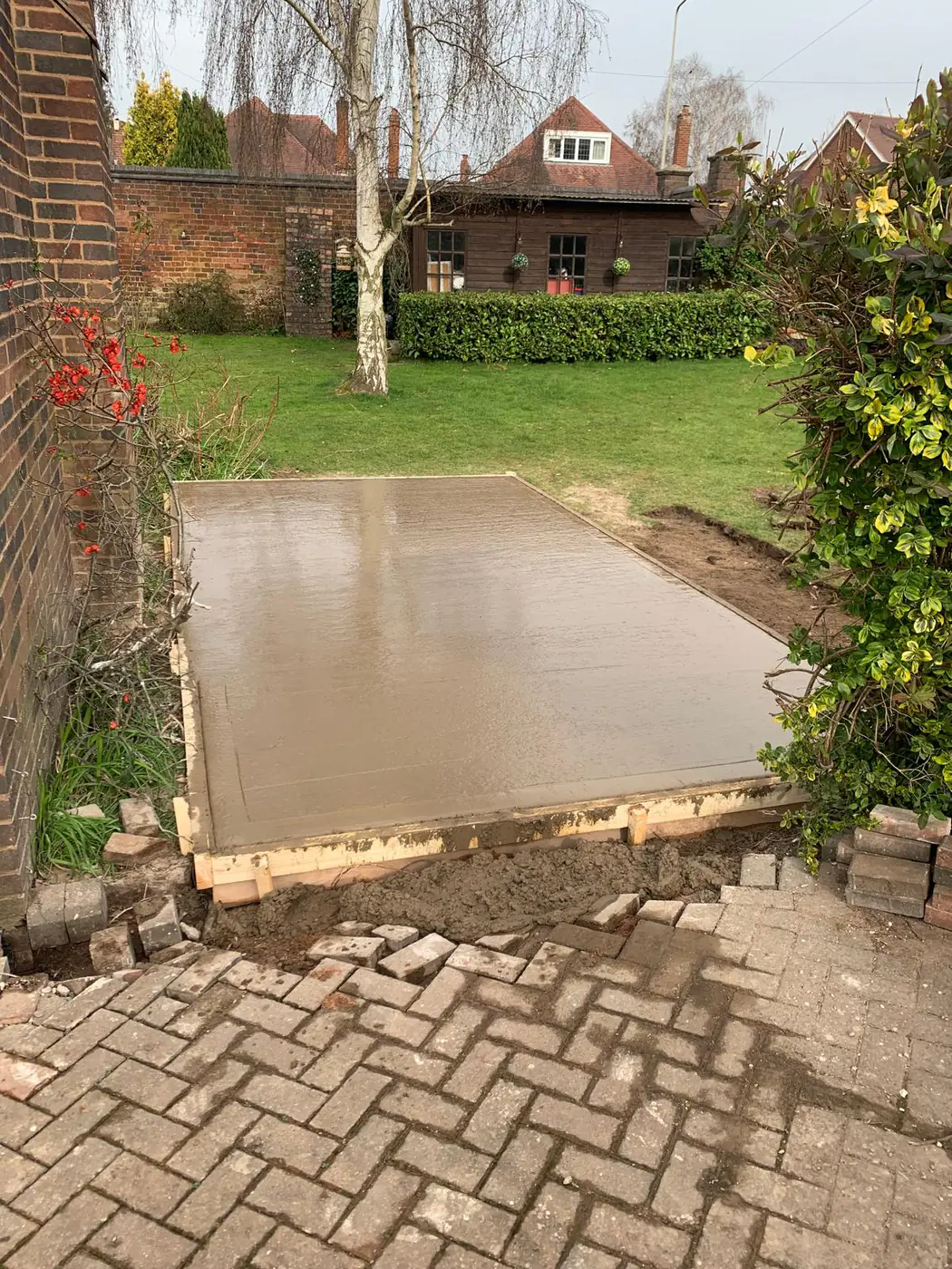 Freshly poured base in a mature lawned garden