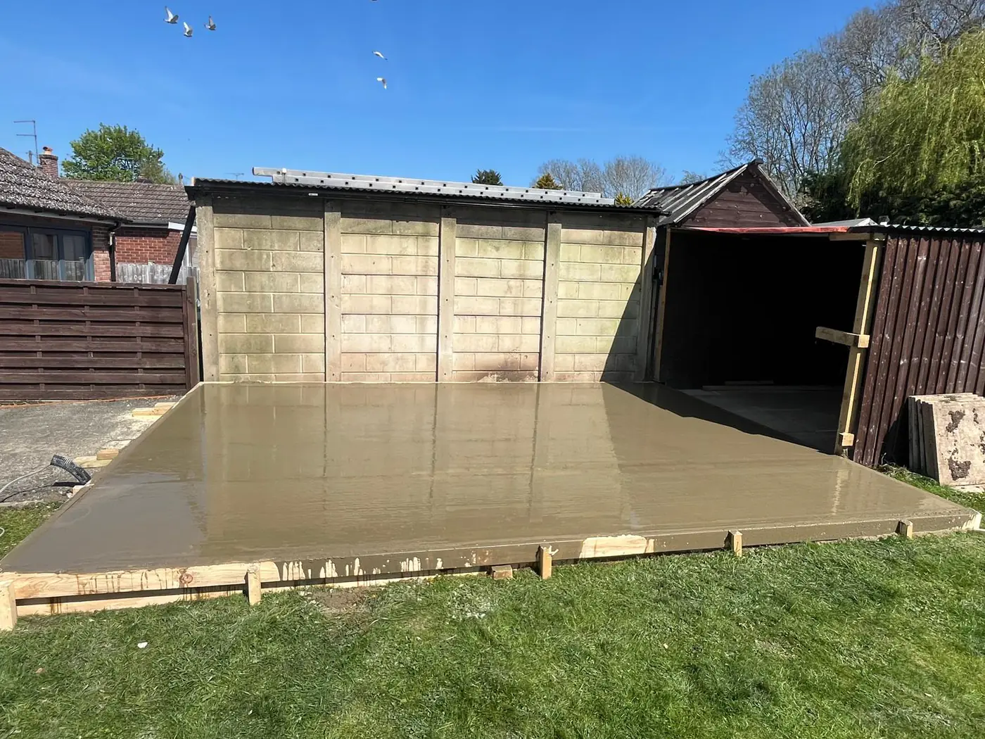 Freshly poured base alongside an existing garage