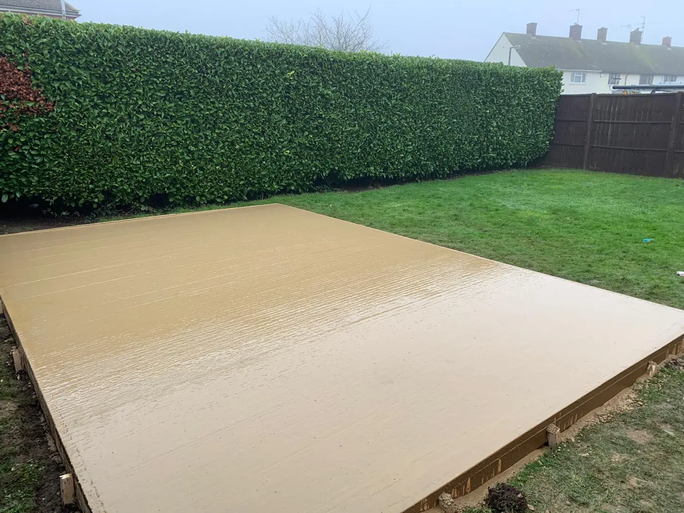 Freshly poured base framed by a clipped laurel hedge