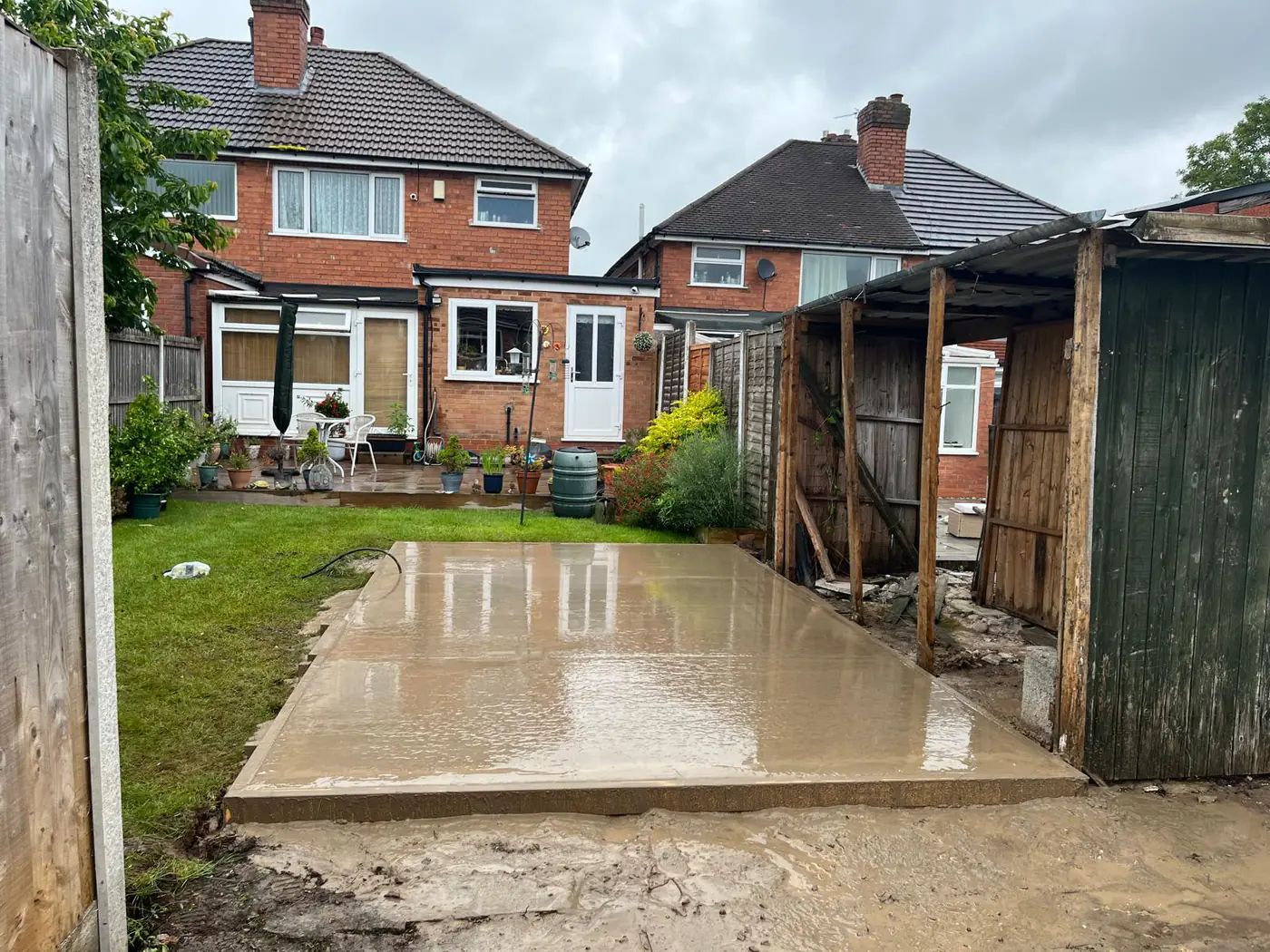 Freshly poured base alongside a house extension