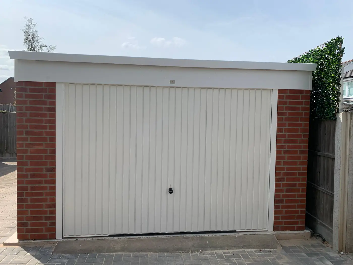 Completed garage with cream door and red brick piers