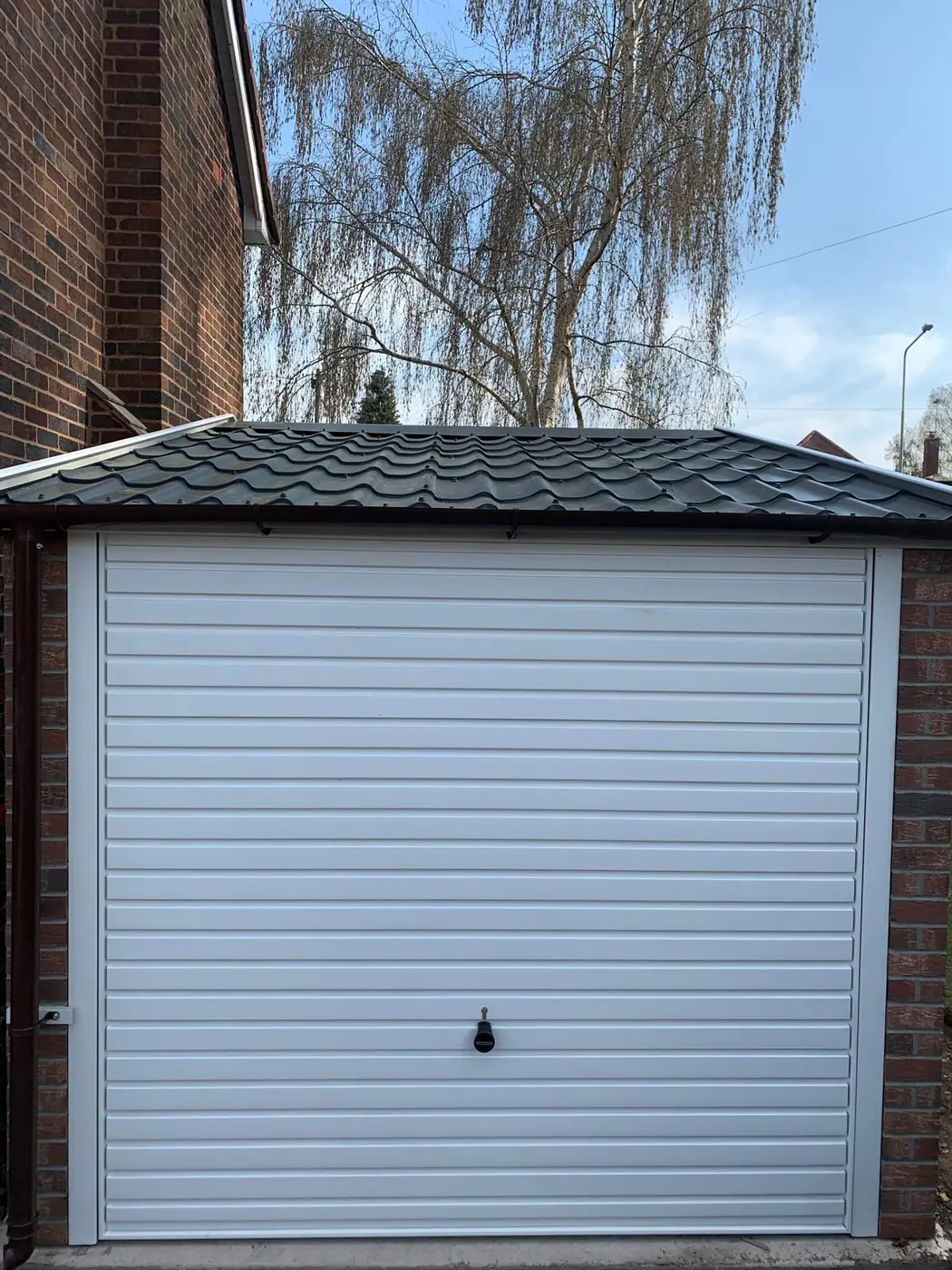 Completed garage with white roller door and tiled roof